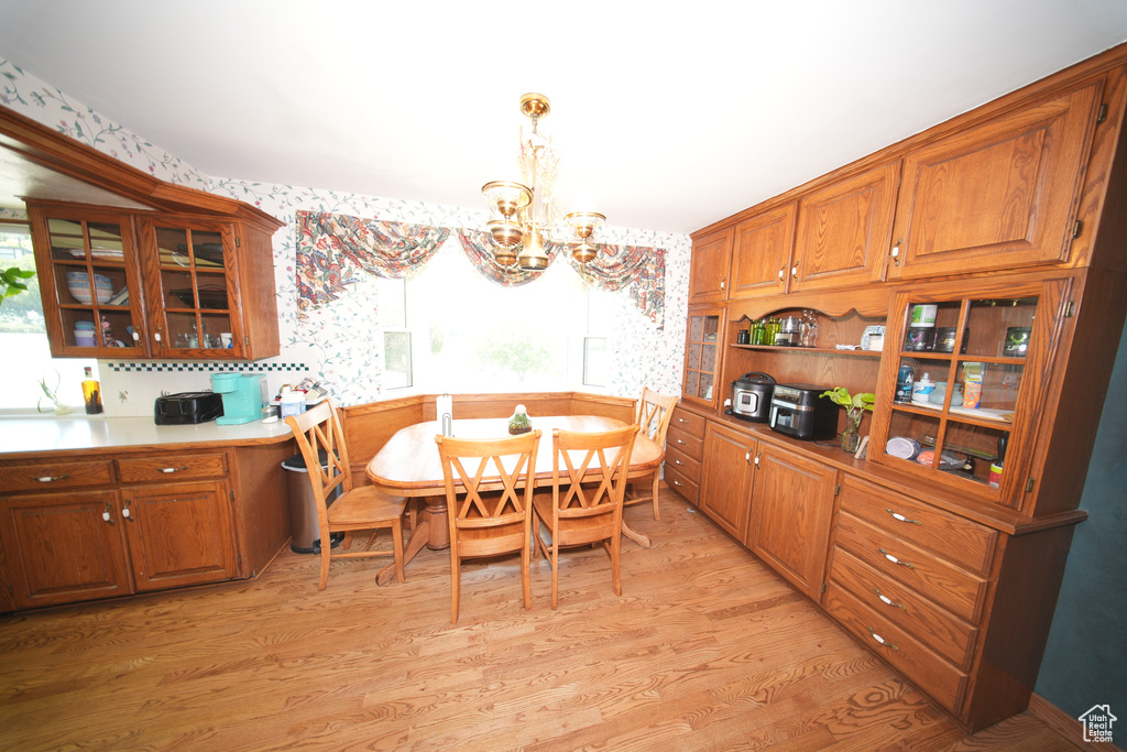 Dining space featuring a chandelier, wallpapered walls, light wood-type flooring, and plenty of natural light