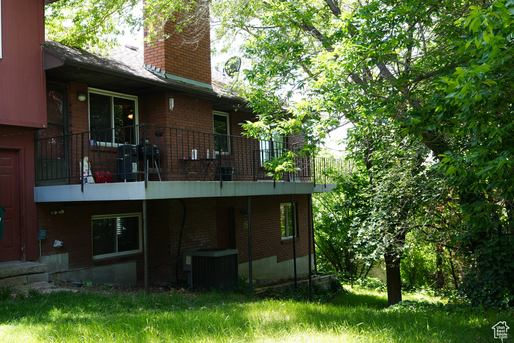 Rear view of house with central AC, a chimney, and brick siding