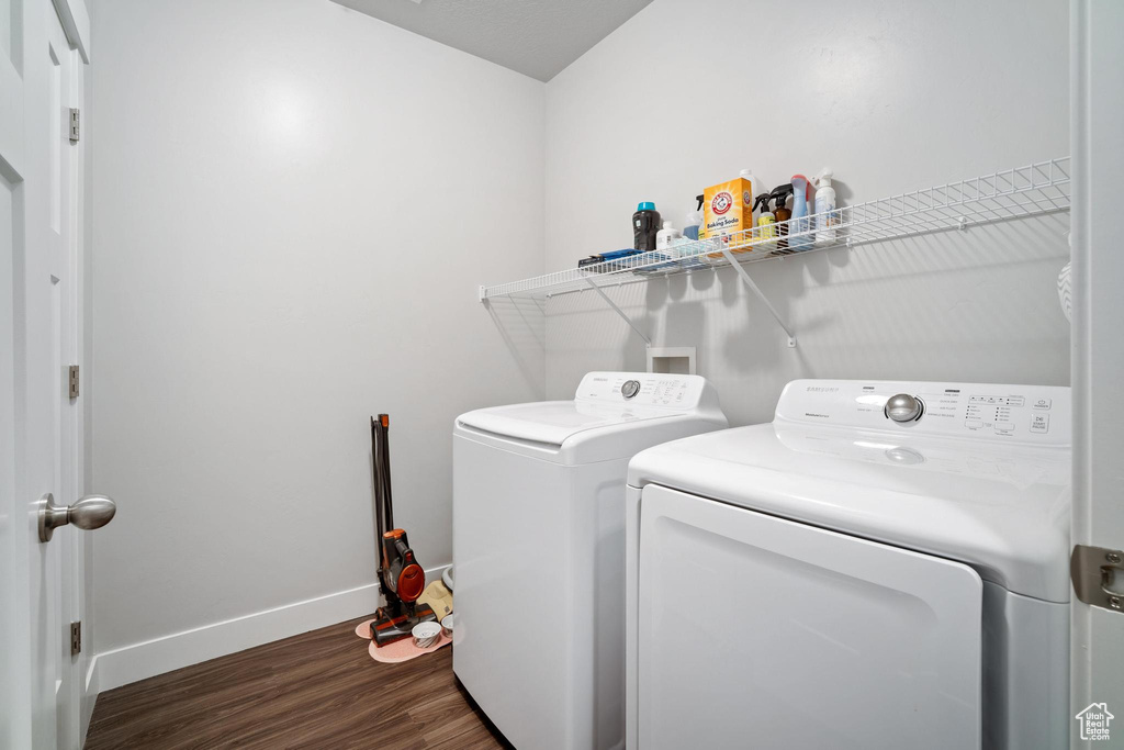 Washroom with washer and dryer, wood finished floors, and baseboards