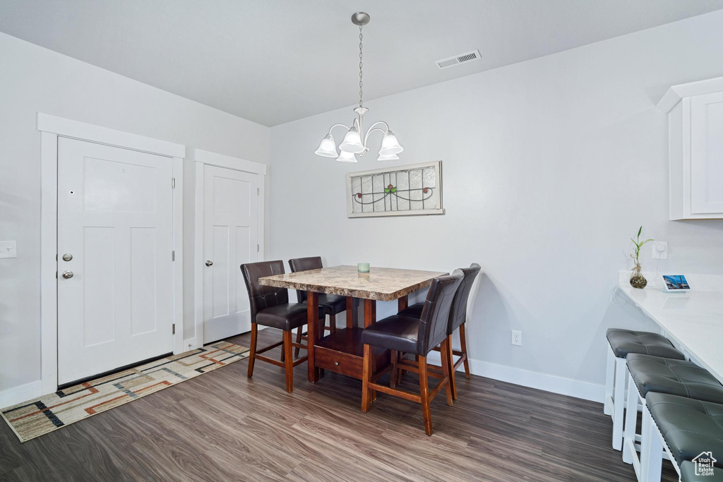 Dining area featuring wood finished floors, a chandelier, and baseboards