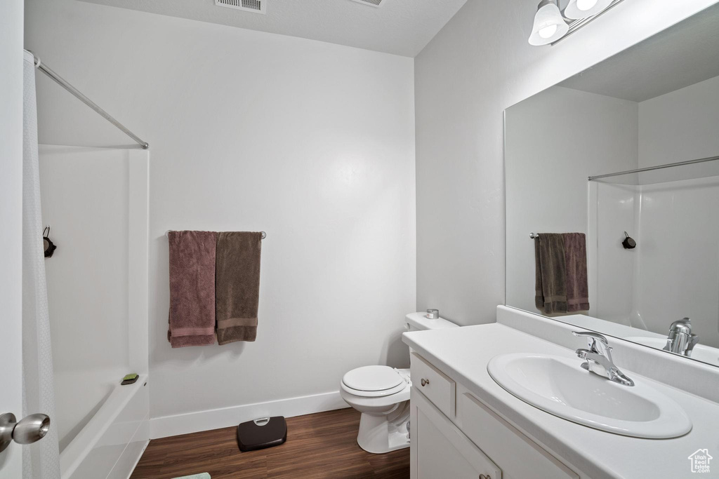 Full bathroom featuring vanity, baseboards, wood finished floors, toilet, and shower / tub combo with curtain