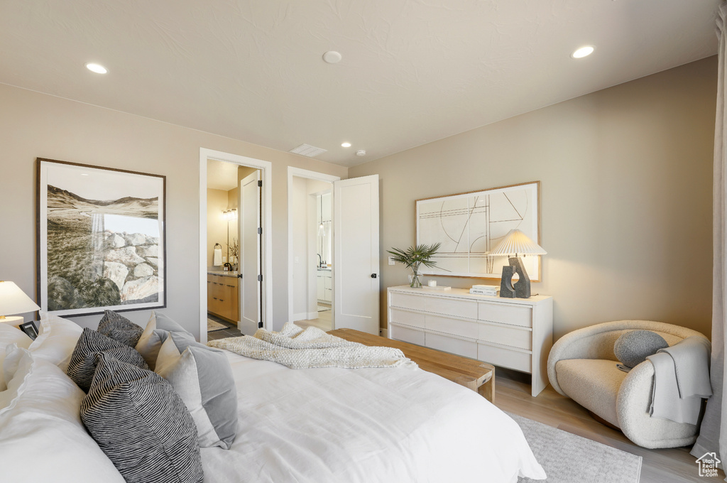 Bedroom with light wood finished floors, recessed lighting, and ensuite bath