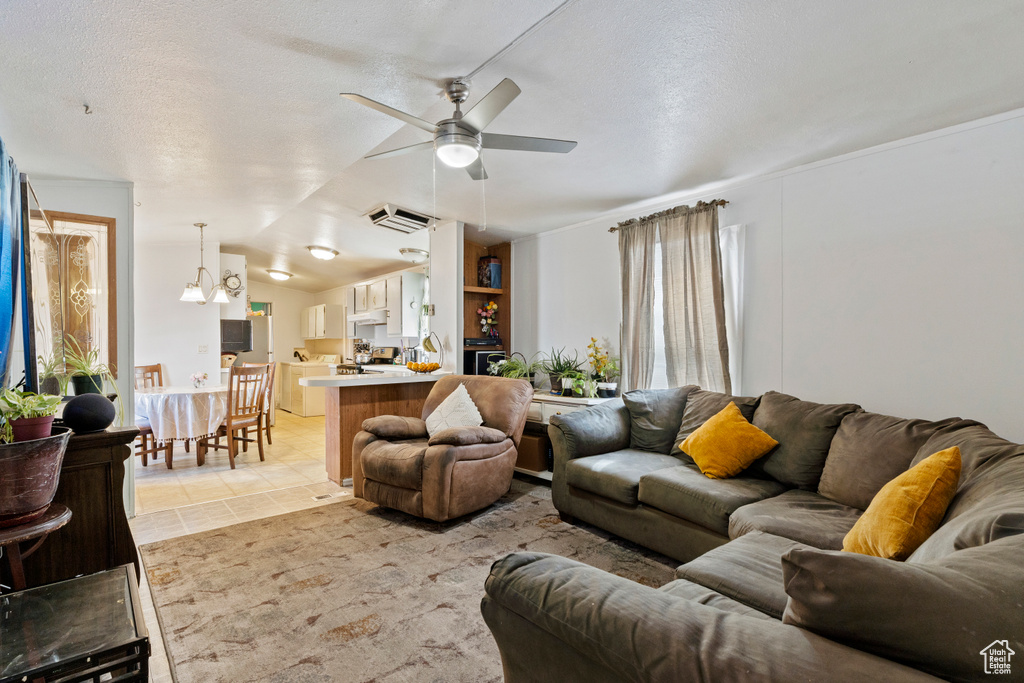 Living room featuring ceiling fan, a textured ceiling, and vaulted ceiling