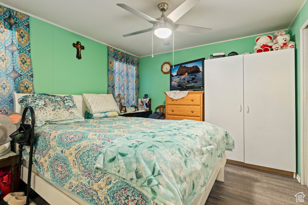 Bedroom featuring wood finished floors, ornamental molding, and ceiling fan