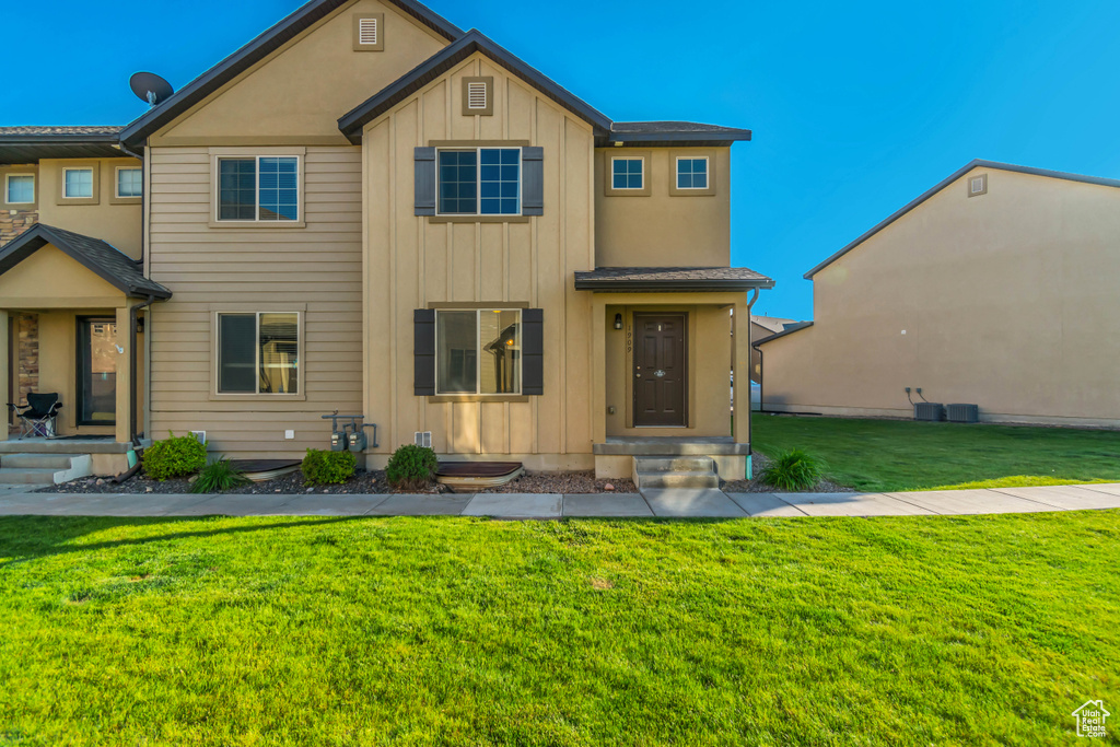 Townhome / multi-family property with board and batten siding and a front yard