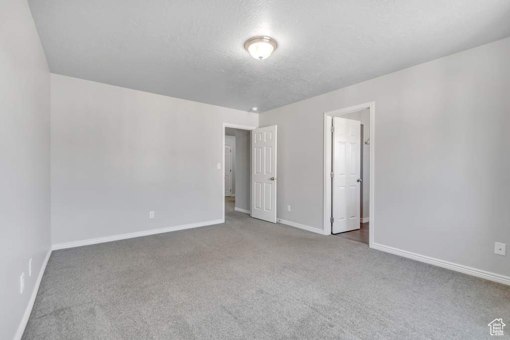 Unfurnished bedroom with carpet floors, baseboards, and a textured ceiling