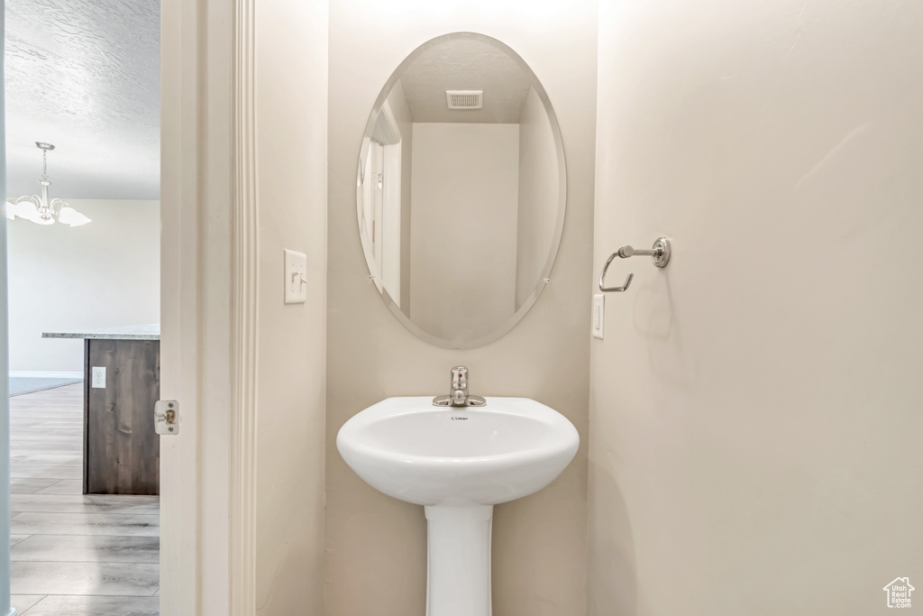 Bathroom featuring a chandelier, a textured ceiling, and wood finished floors