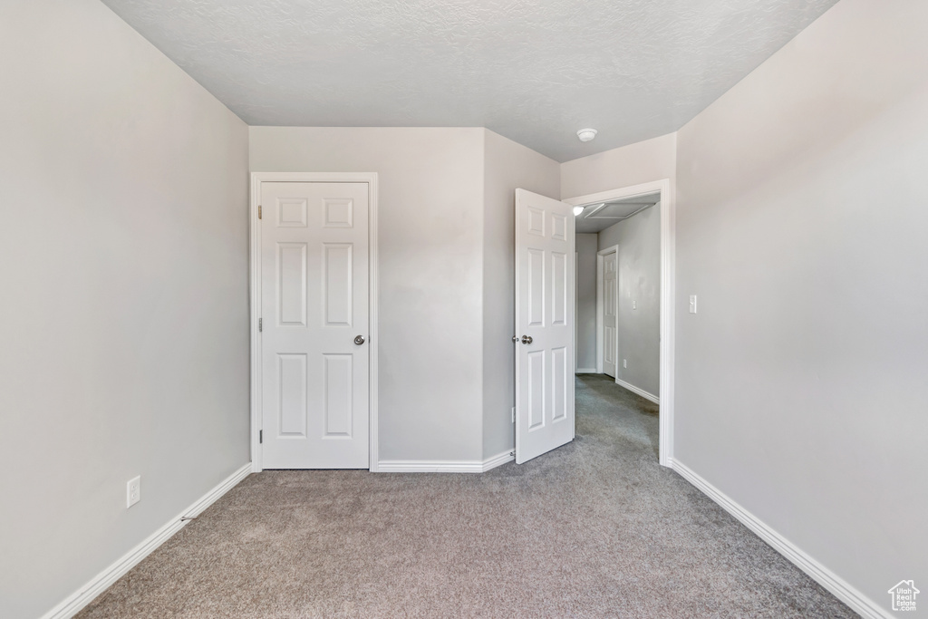 Unfurnished bedroom with carpet floors, baseboards, and a textured ceiling