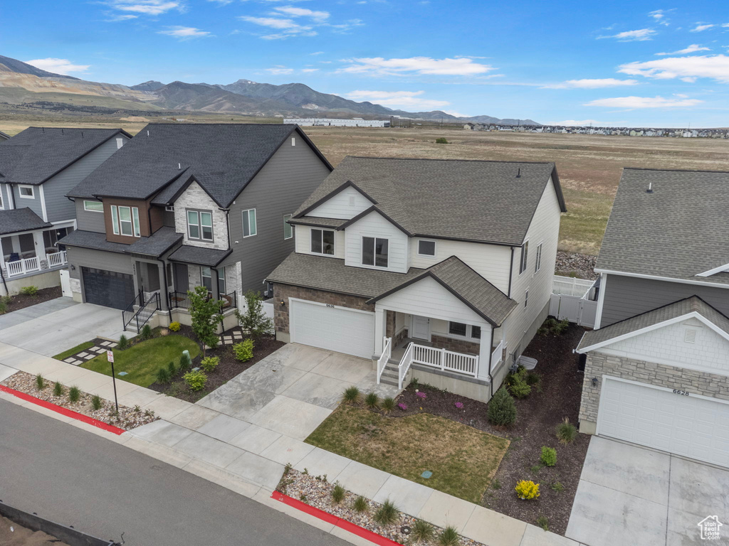 View of front of home featuring concrete driveway, covered porch, a mountain view, a shingled roof, and a residential view