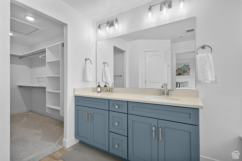 Bathroom featuring double vanity, a spacious closet, wood finished floors, and baseboards