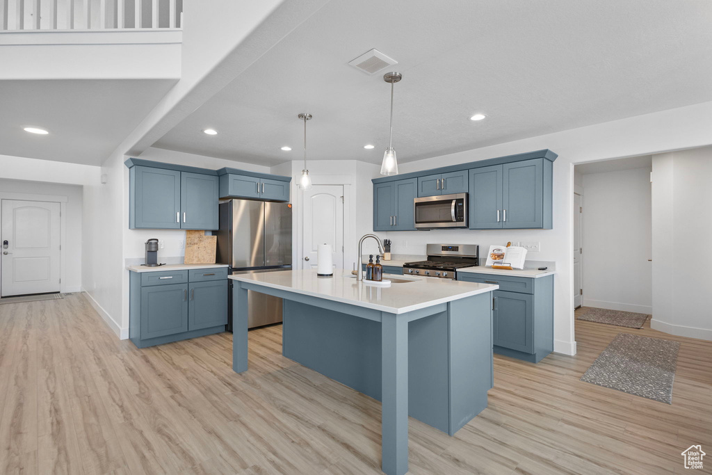Kitchen featuring stainless steel appliances, a sink, baseboards, blue cabinetry, and recessed lighting