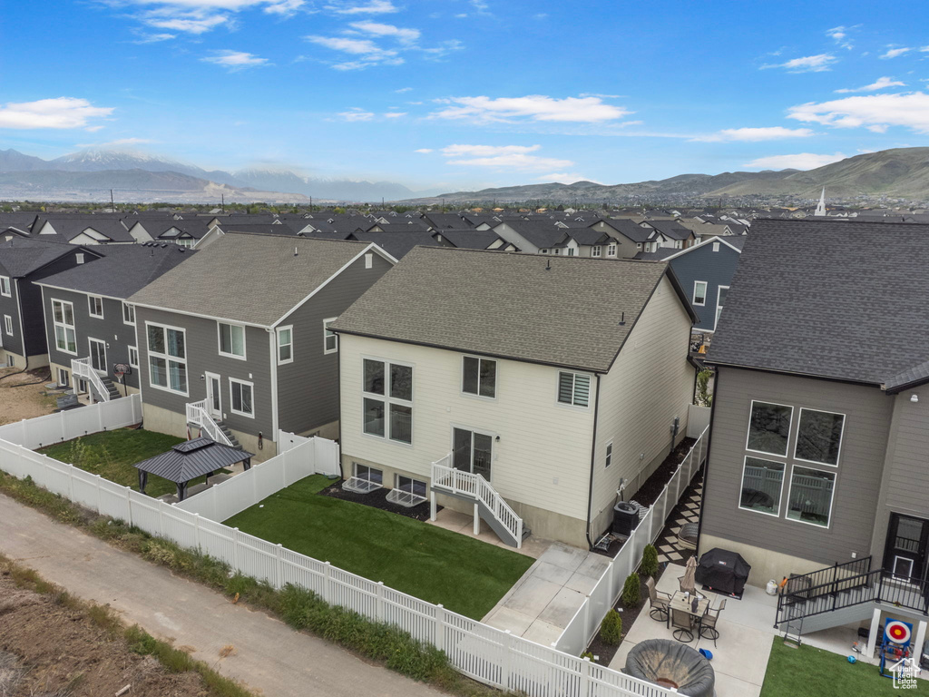 Back of property with a residential view, a mountain view, a patio, and roof with shingles