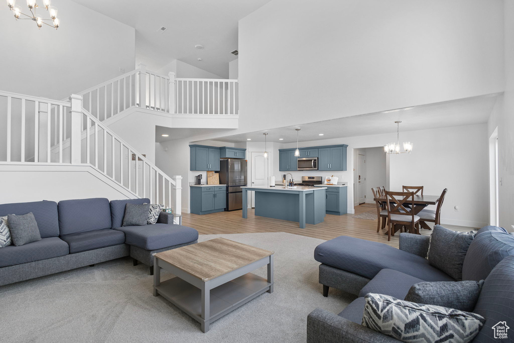 Living room featuring a chandelier, a towering ceiling, stairs, and light wood finished floors
