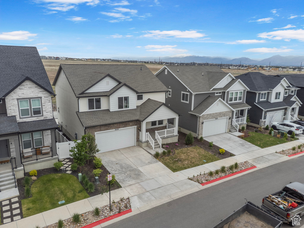 View of front of house featuring a residential view, concrete driveway, an attached garage, a shingled roof, and a mountain view