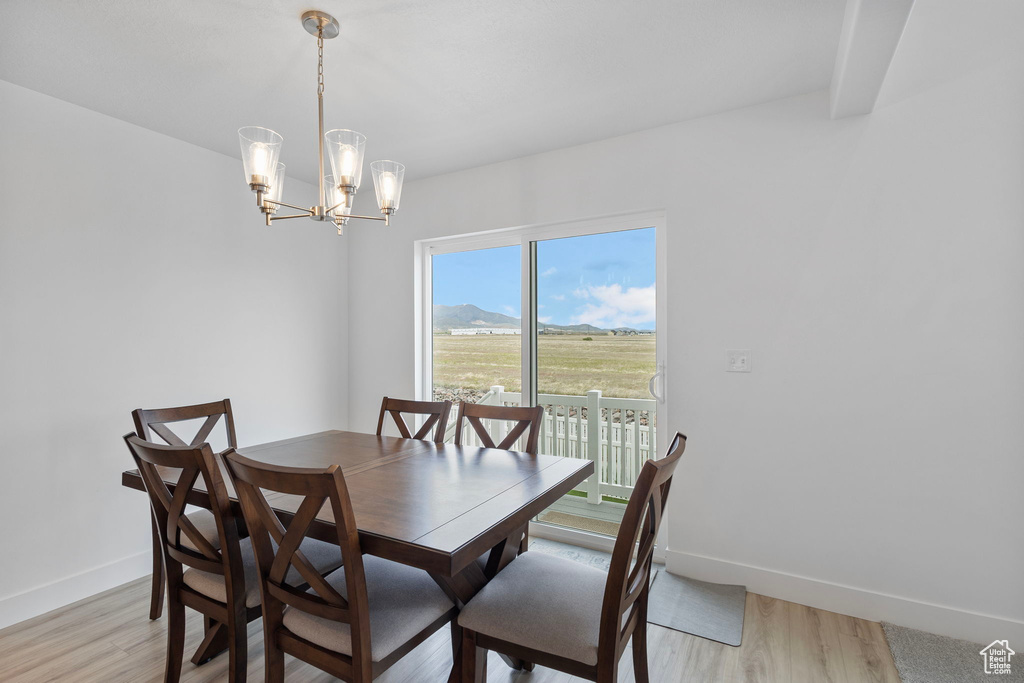 Dining area with baseboards, light wood-style floors, a chandelier, and a mountain view