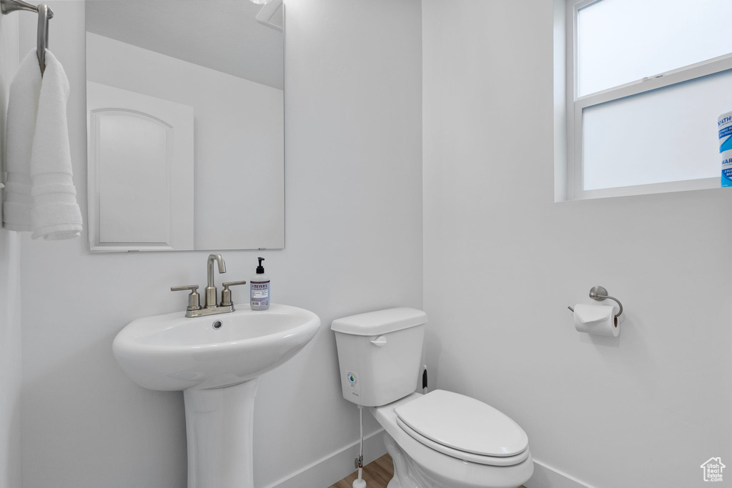 Bathroom featuring baseboards, toilet, and a sink