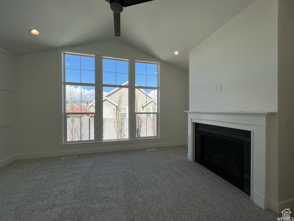 Unfurnished living room with vaulted ceiling, a fireplace, baseboards, a ceiling fan, and carpet floors