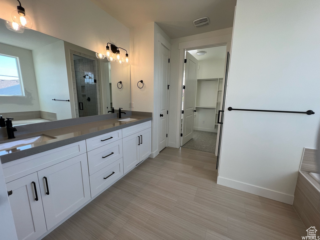 Bathroom with a stall shower, double vanity, a bath, a walk in closet, and baseboards