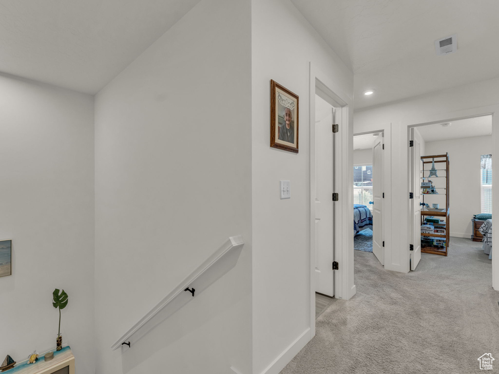 Hall with an upstairs landing, light carpet, healthy amount of natural light, baseboards, and recessed lighting