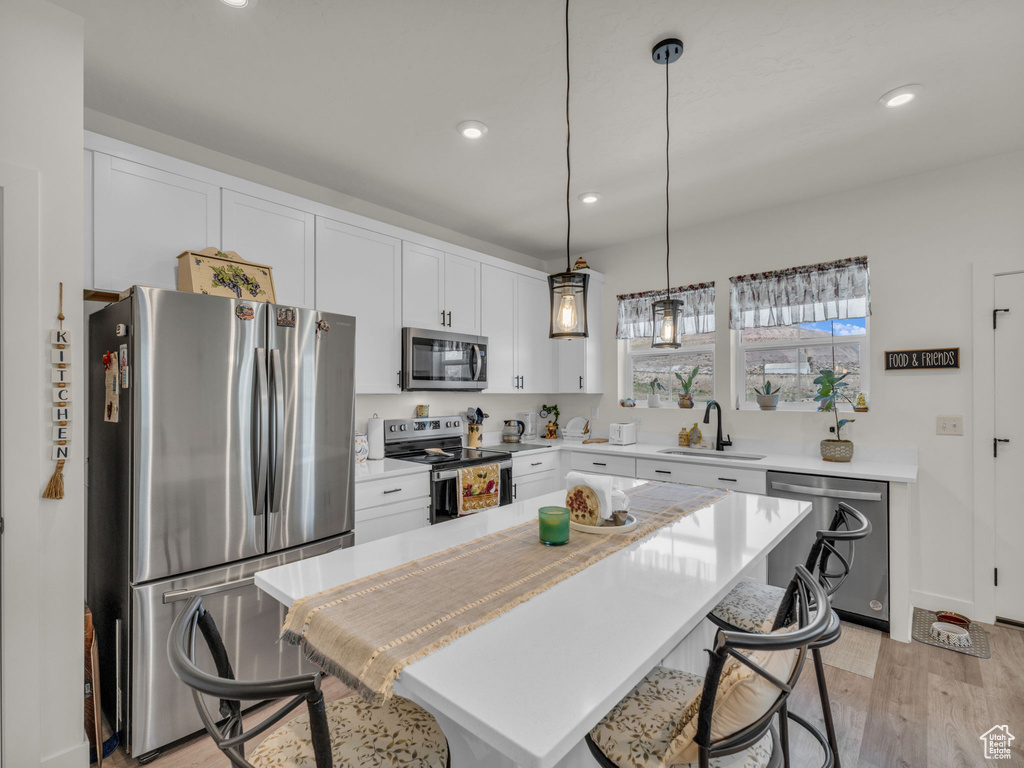Kitchen featuring stainless steel appliances, a sink, a kitchen breakfast bar, recessed lighting, and light countertops