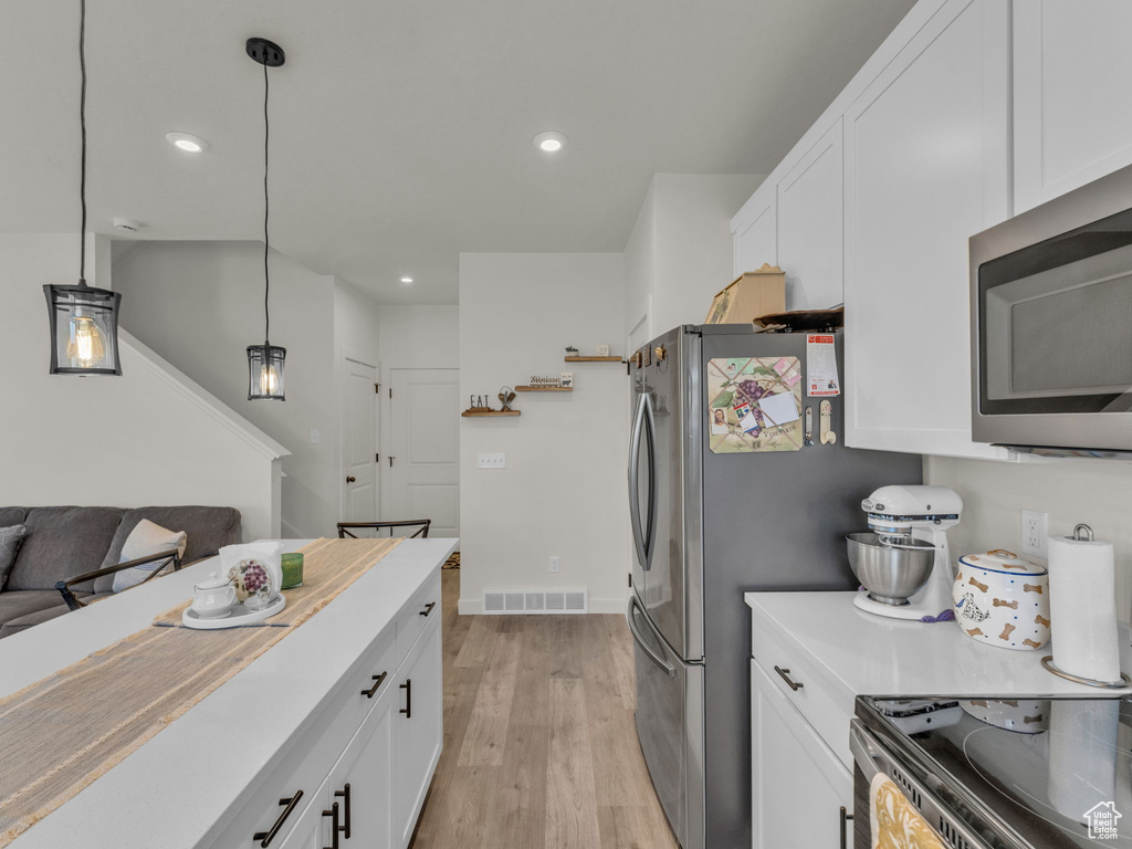 Kitchen with appliances with stainless steel finishes, white cabinets, light countertops, and recessed lighting