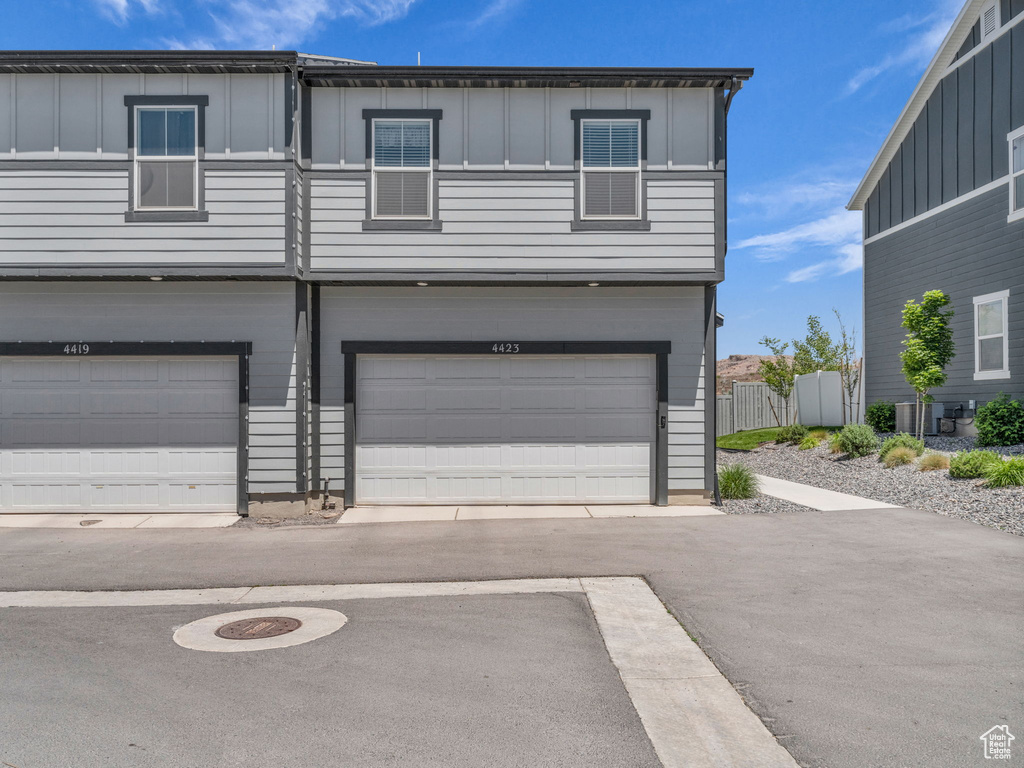 View of front of property featuring board and batten siding, a garage, and central AC unit