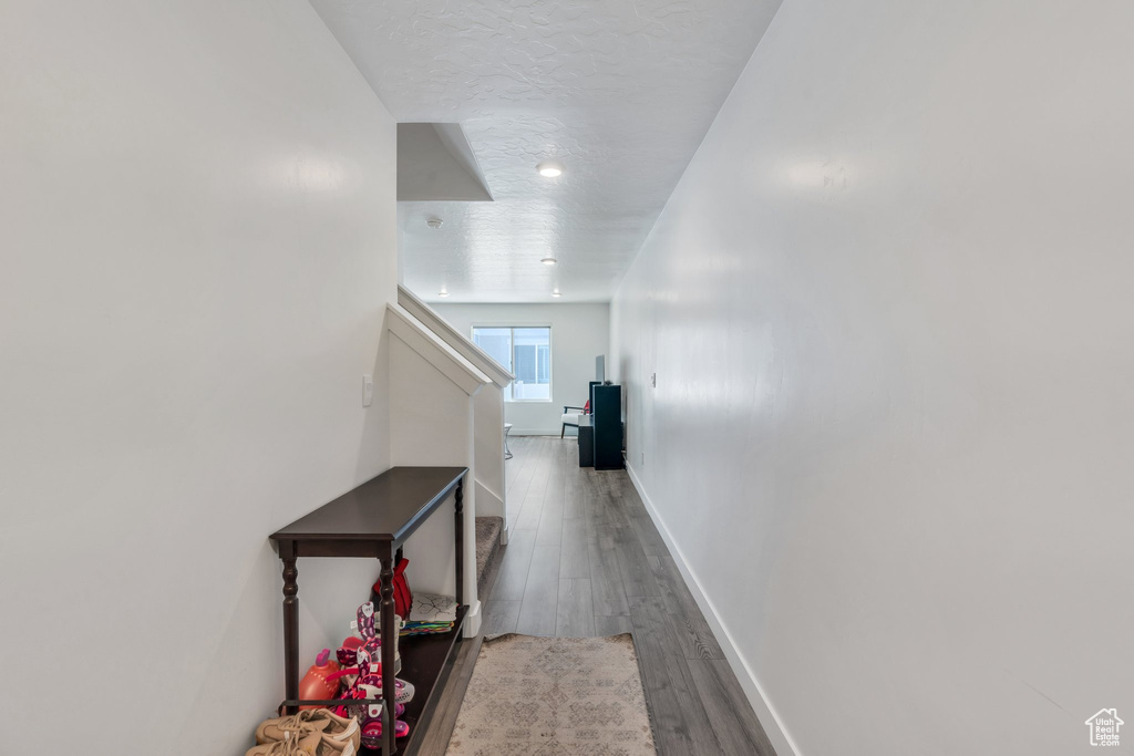 Hallway with wood finished floors, baseboards, a textured ceiling, and stairway