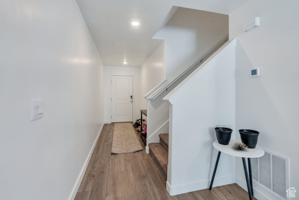 Foyer entrance featuring wood finished floors, baseboards, and stairs