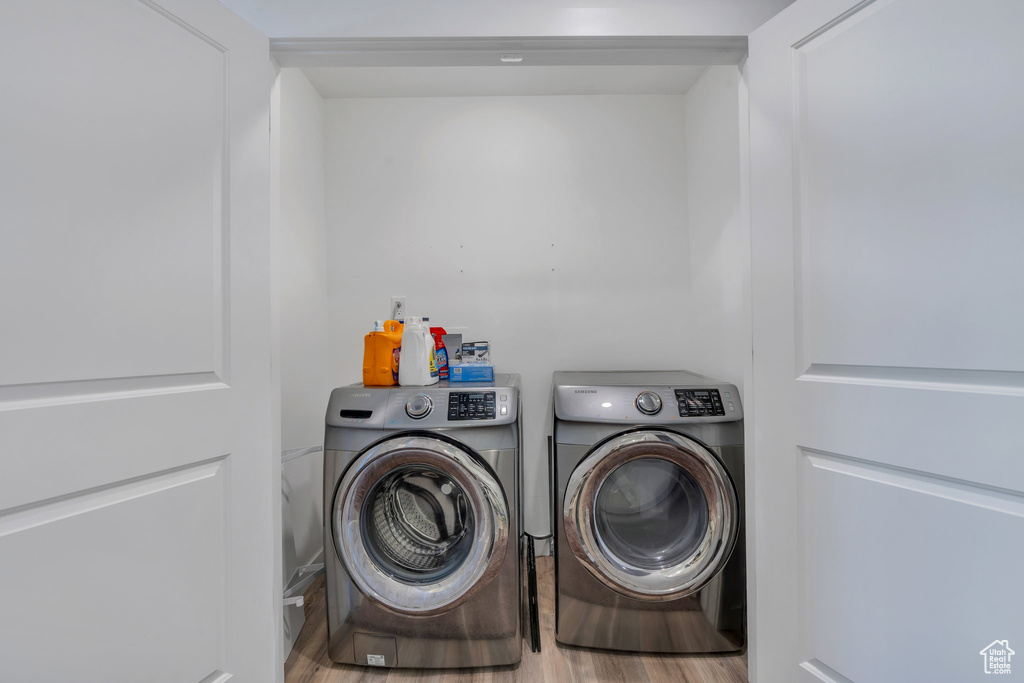 Laundry area featuring separate washer and dryer and wood finished floors