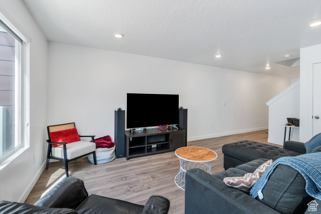 Living room with plenty of natural light, light wood finished floors, baseboards, and recessed lighting