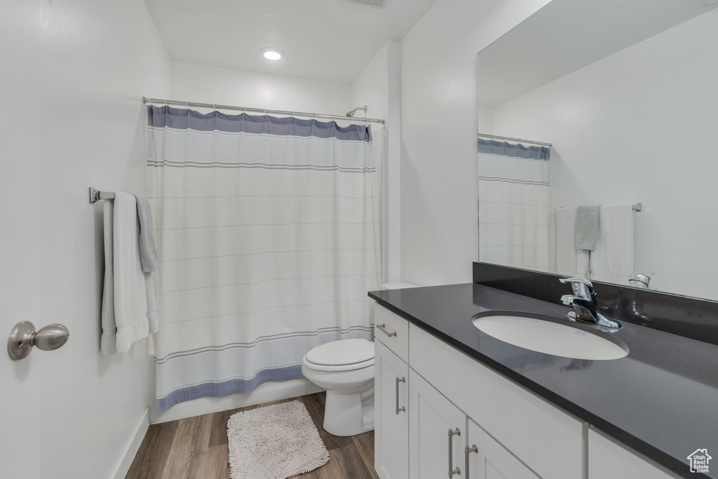 Bathroom featuring vanity, toilet, wood finished floors, and baseboards