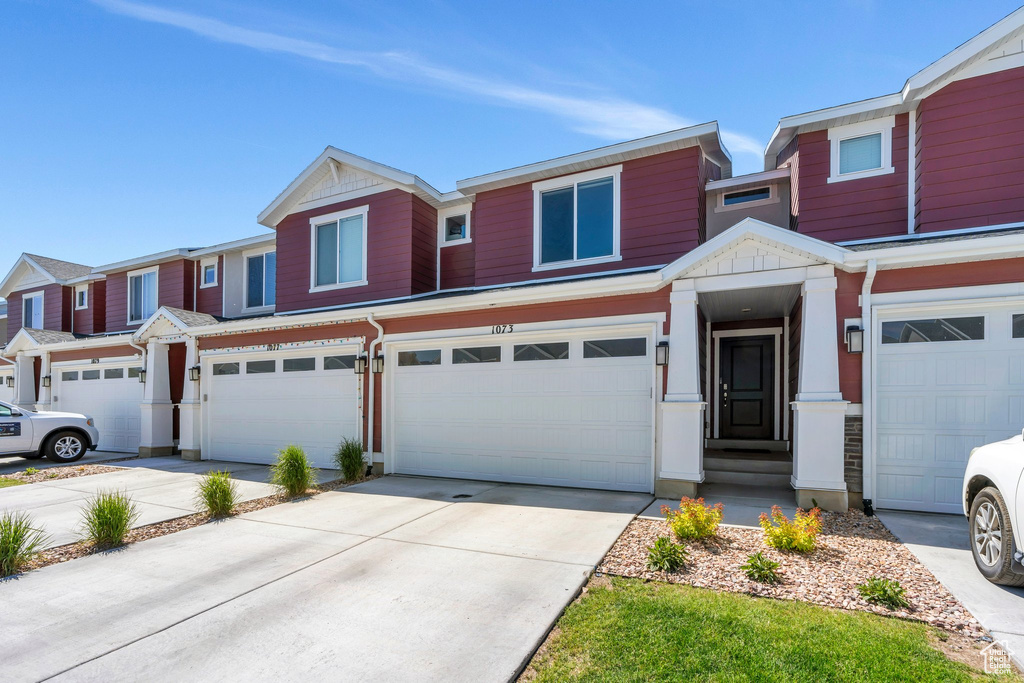 Multi unit property featuring an attached garage and driveway