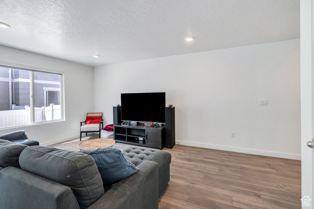 Living area with wood finished floors, baseboards, recessed lighting, and a textured ceiling