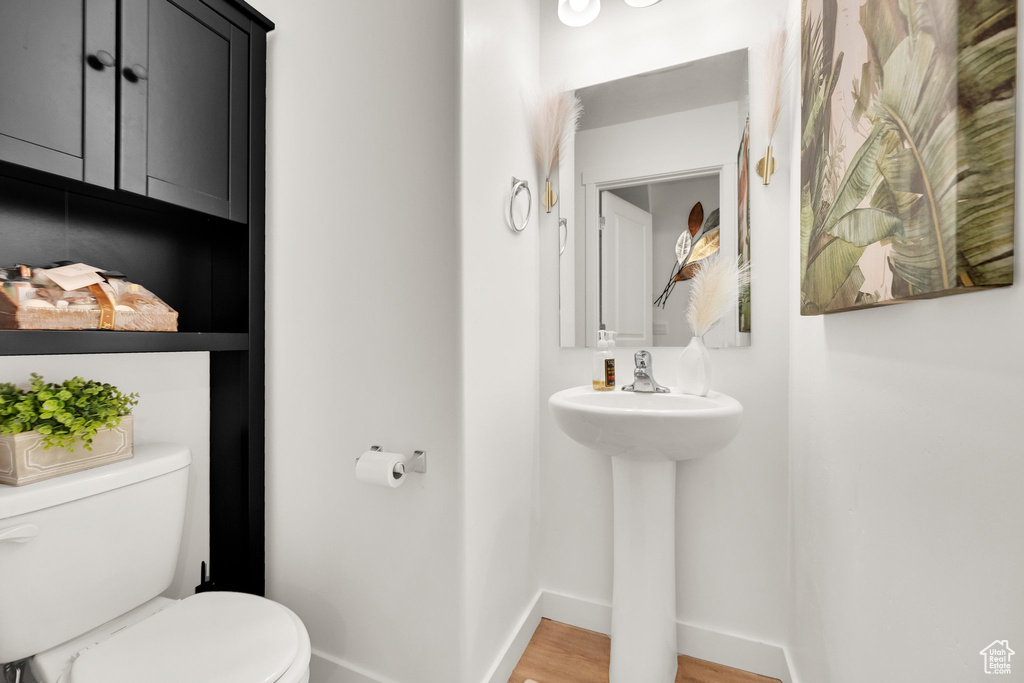 Bathroom featuring toilet, baseboards, and wood finished floors