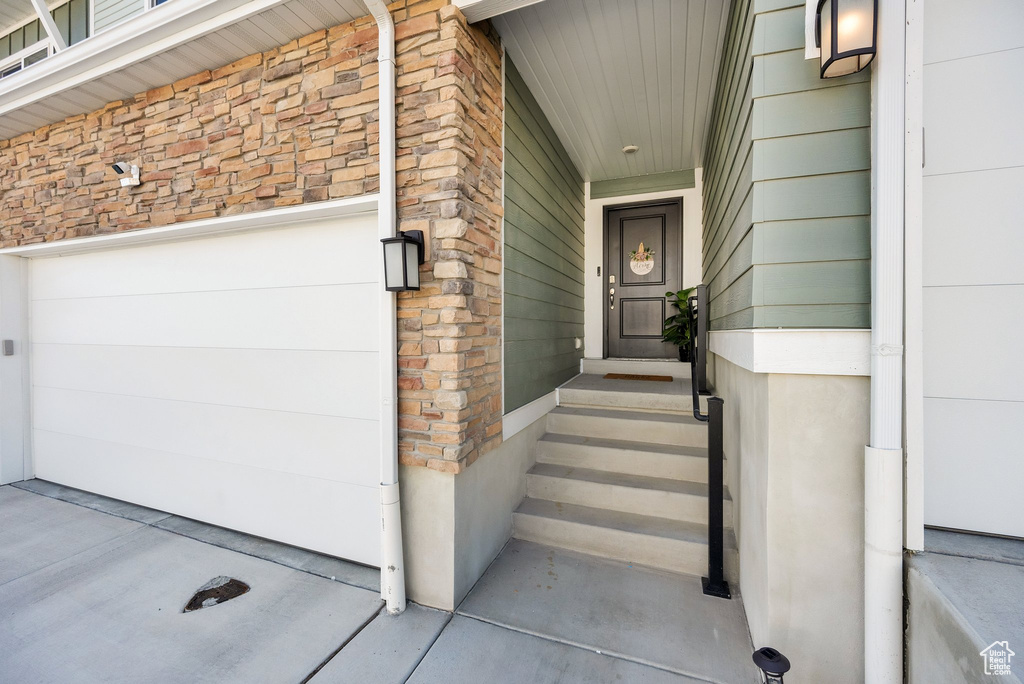 Entrance to property with a garage and stone siding