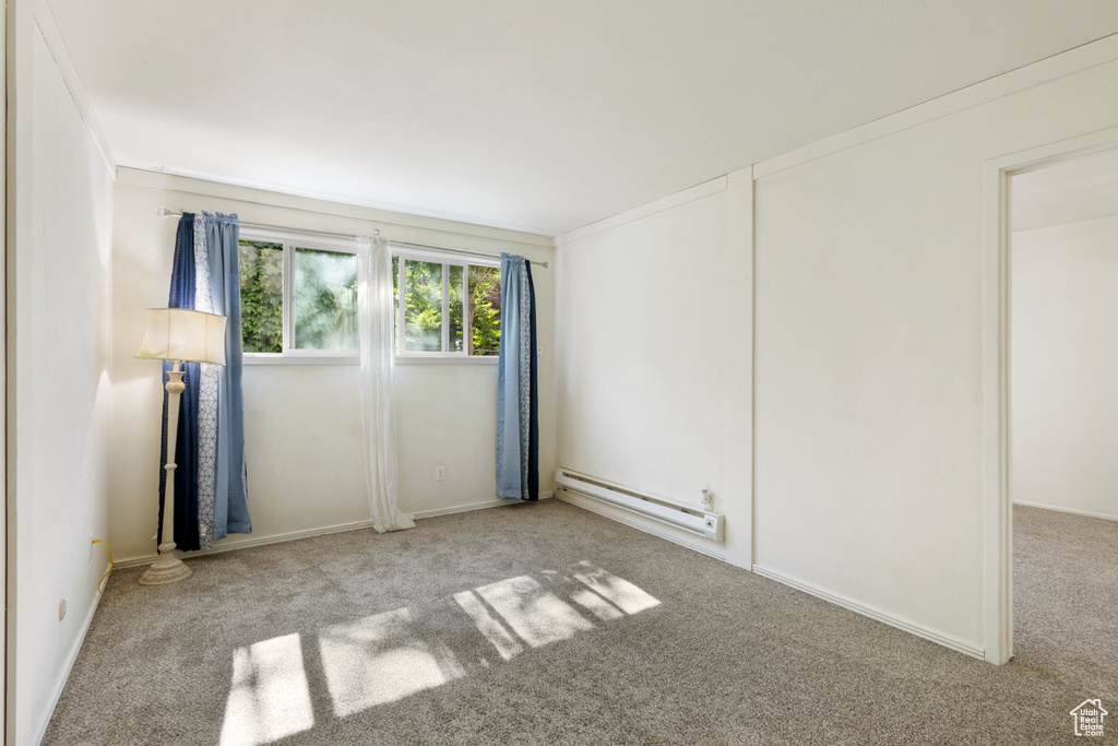 Carpeted spare room featuring a baseboard radiator