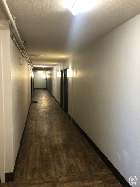 Hallway featuring dark wood finished floors, elevator, and baseboards