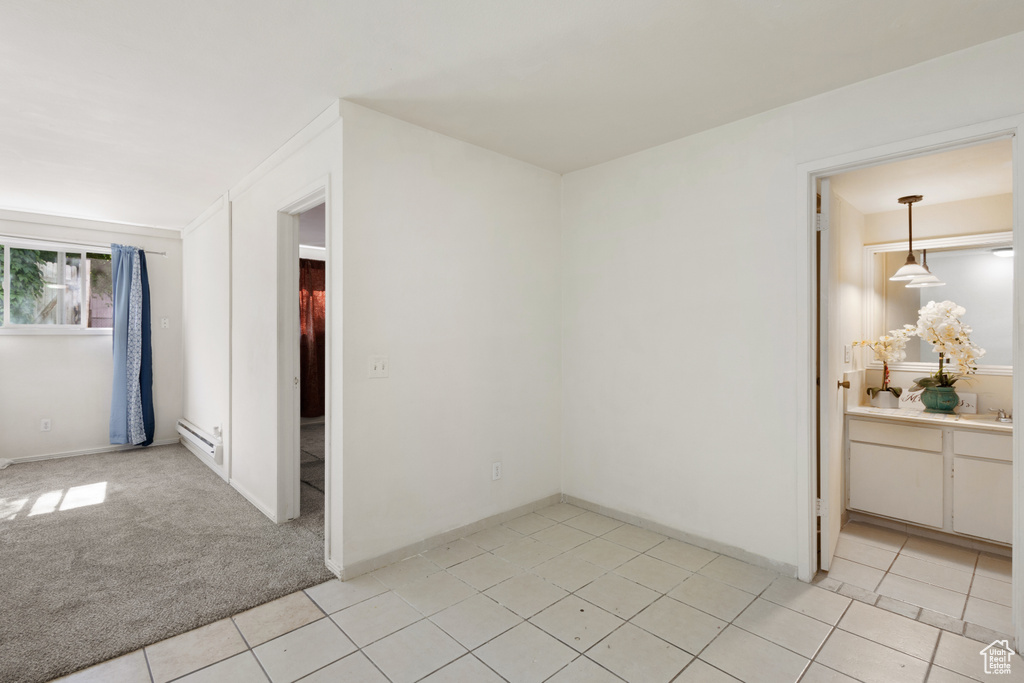 Empty room featuring a baseboard heating unit and light tile patterned flooring