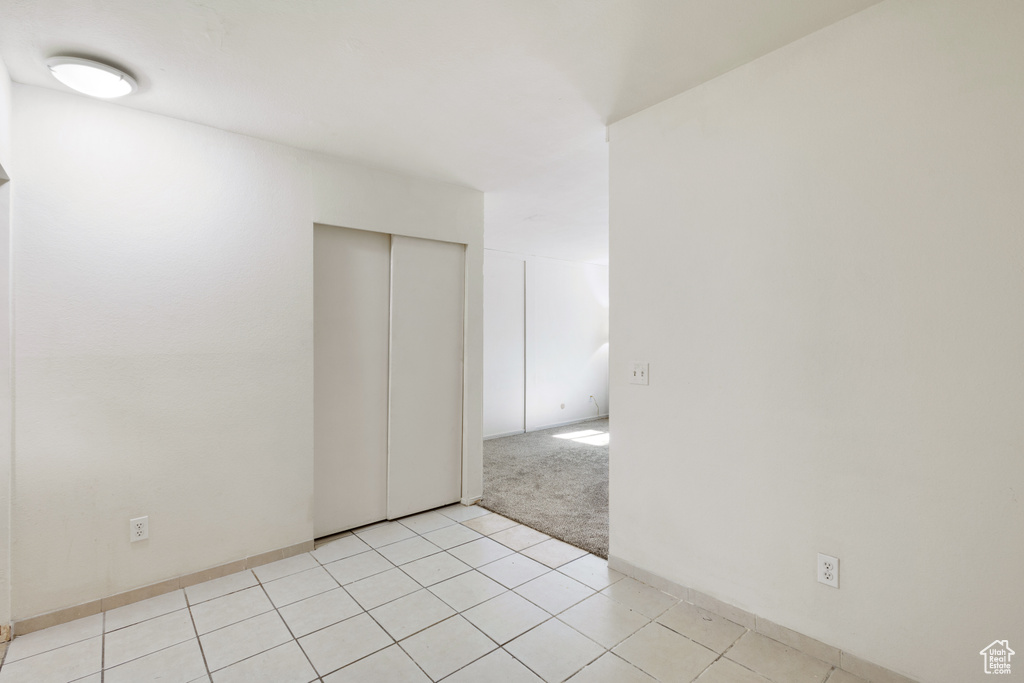 Empty room with light tile patterned floors and light carpet