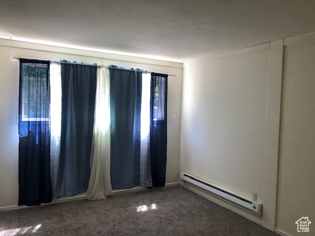 Carpeted spare room with a baseboard heating unit