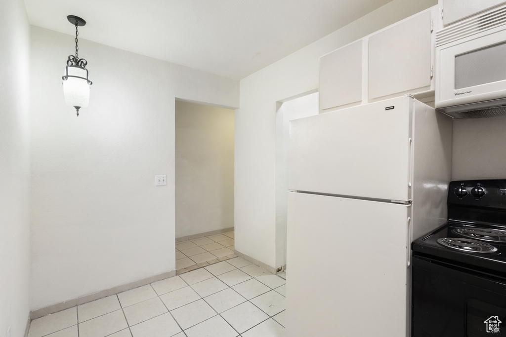 Kitchen with white appliances, white cabinets, baseboards, decorative light fixtures, and light tile patterned floors