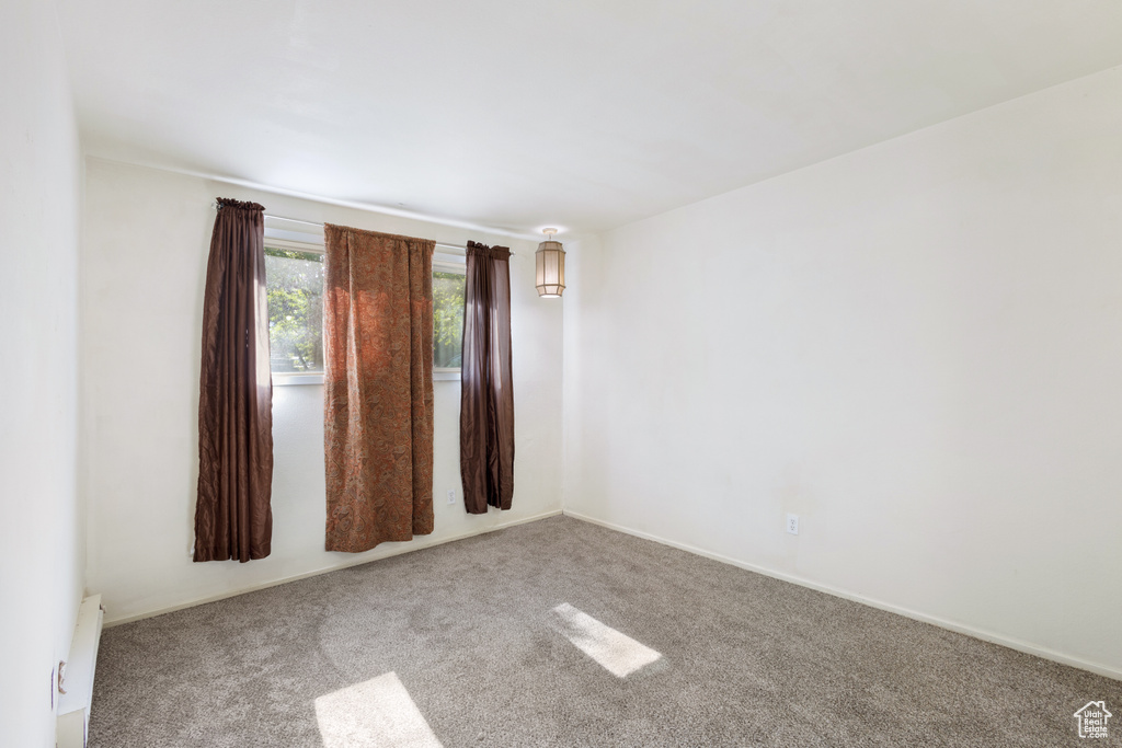 Empty room with carpet flooring, a baseboard radiator, and baseboards