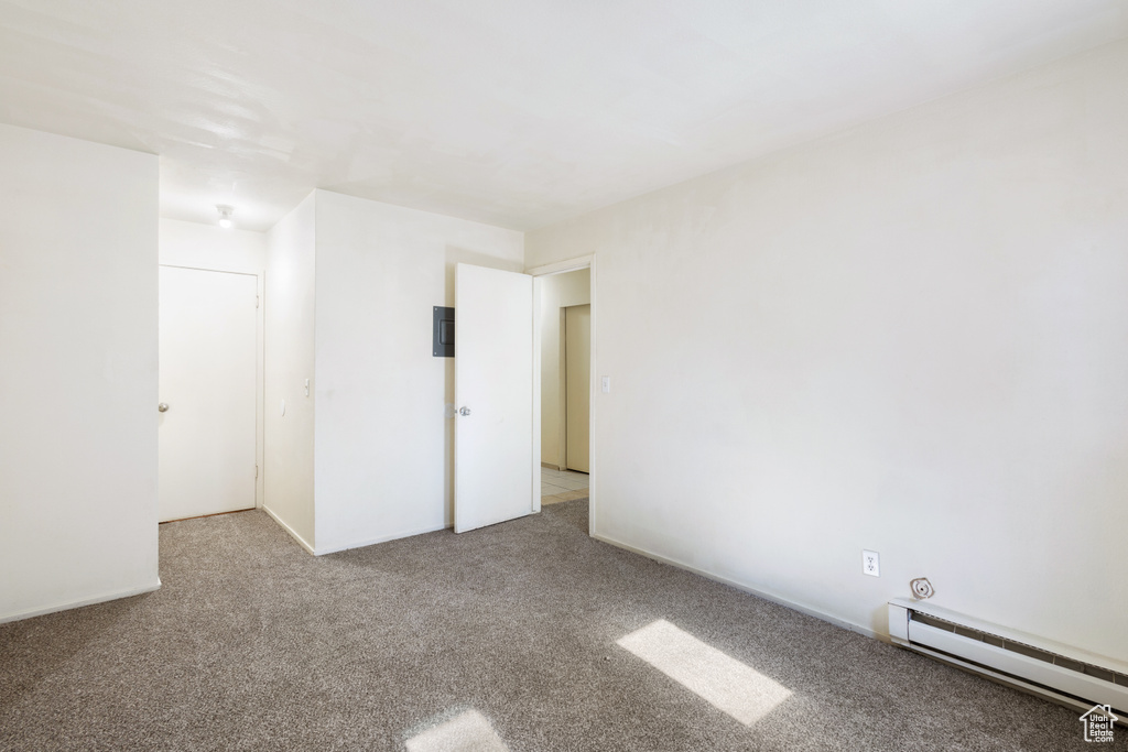 Carpeted spare room with a baseboard heating unit