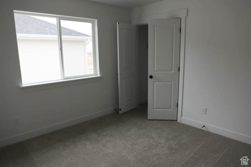 Unfurnished bedroom with carpet, multiple windows, and baseboards