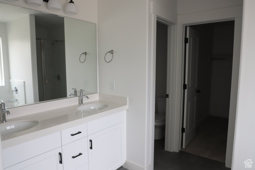 Full bath with double vanity, toilet, and a shower