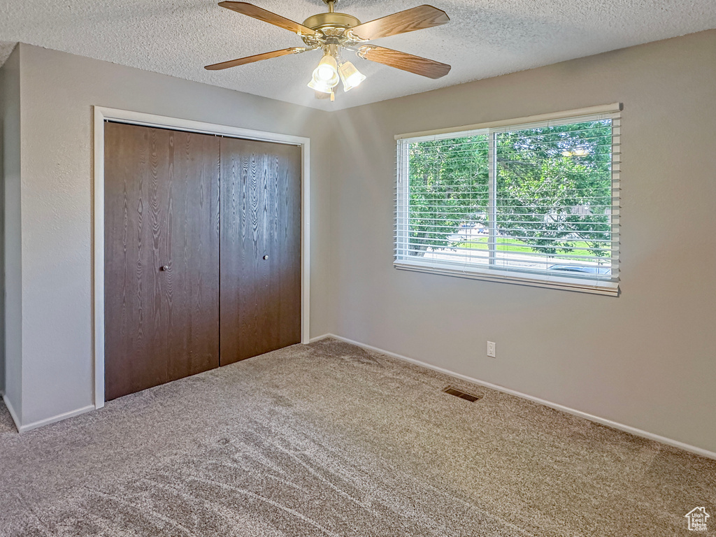 Unfurnished bedroom with carpet floors, a closet, a textured ceiling, a ceiling fan, and baseboards