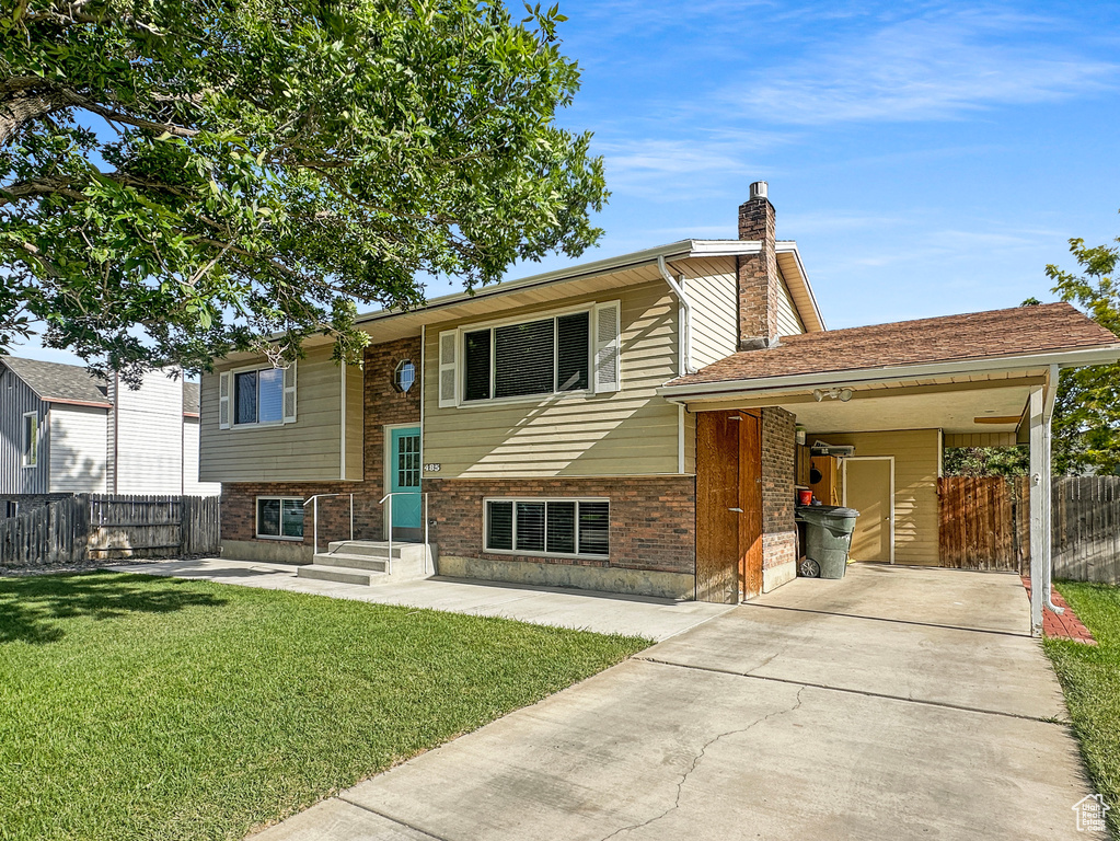View of front of home with brick siding, a chimney, a carport, and driveway