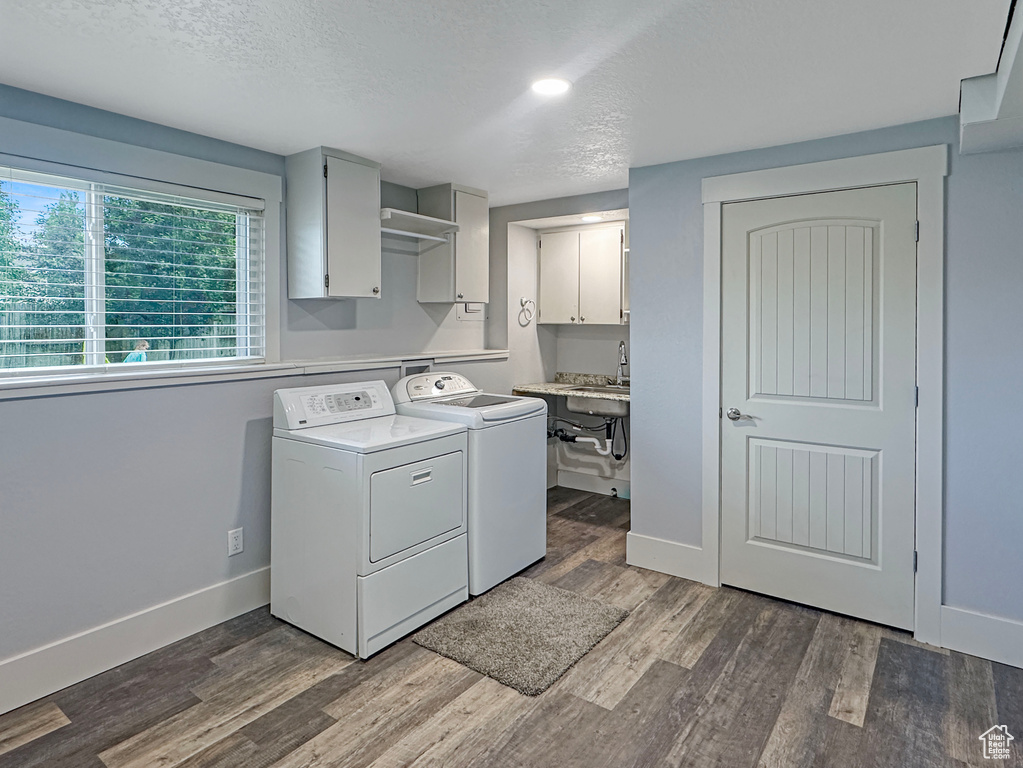Washroom with independent washer and dryer, cabinet space, dark wood-style flooring, baseboards, and a textured ceiling