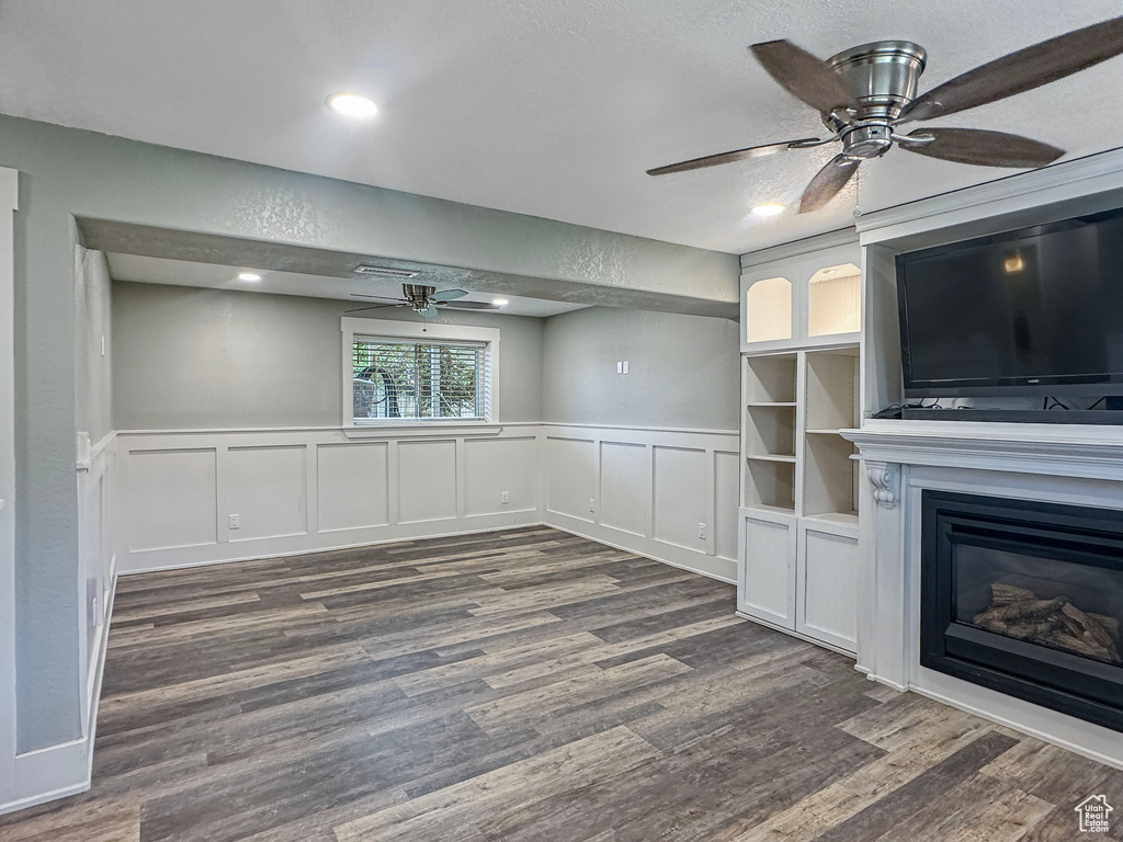 Unfurnished living room with a ceiling fan, dark wood-style floors, a decorative wall, wainscoting, and recessed lighting
