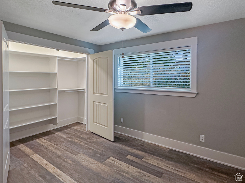 Unfurnished bedroom featuring dark wood finished floors, baseboards, a closet, a textured ceiling, and a ceiling fan